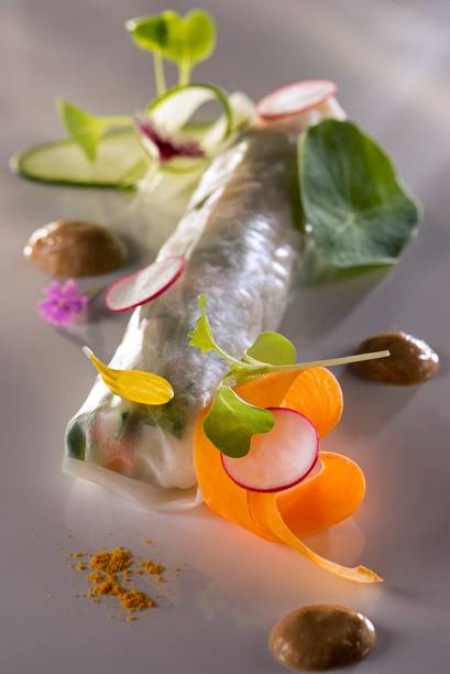 Enrolado de legumes e flores na folha de arroz, servido com molho de castanha-de-baru Enrolado de legumes e flores na folha de arroz, servido com molho de castanha-de-baru