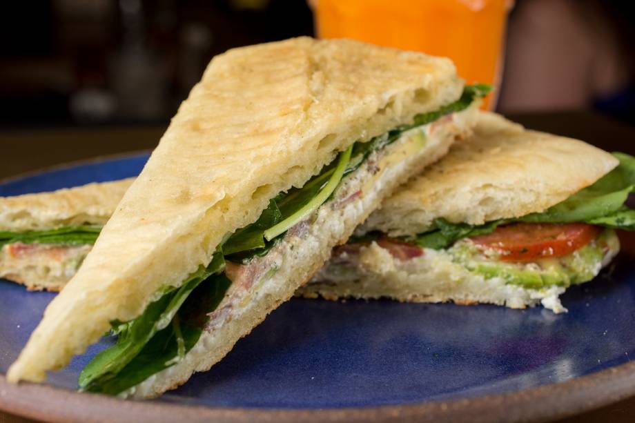 Sanduíche de rúcula, queijo de cabra, tomate, lâminas de abacate e molho pesto