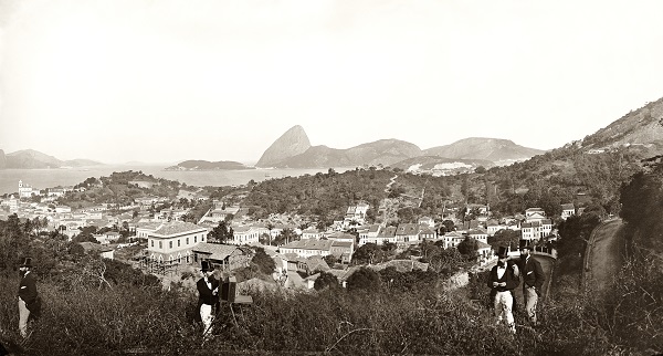 Paisagem de Santa Teresa, por Marc Ferrez (c. 1885). Aqui, mais curioso do que a paisagem (com a Rua Cândido Mendes, que sobe da Glória, no canto inferior direito) é a dupla aparição do próprio Ferrez, de calça mais clara, e de um amigo desconhecido na foto. A explicação é simples: a câmera era dotada de um mecanismo de varredura, que produzia uma imagem ao longo de vários minutos a partir de cliques sucessivos. Enquanto o equipamento fazia a panorâmica, os amigos mudavam de lugar diante da lente para aparecer duas vezes na mesma imagem