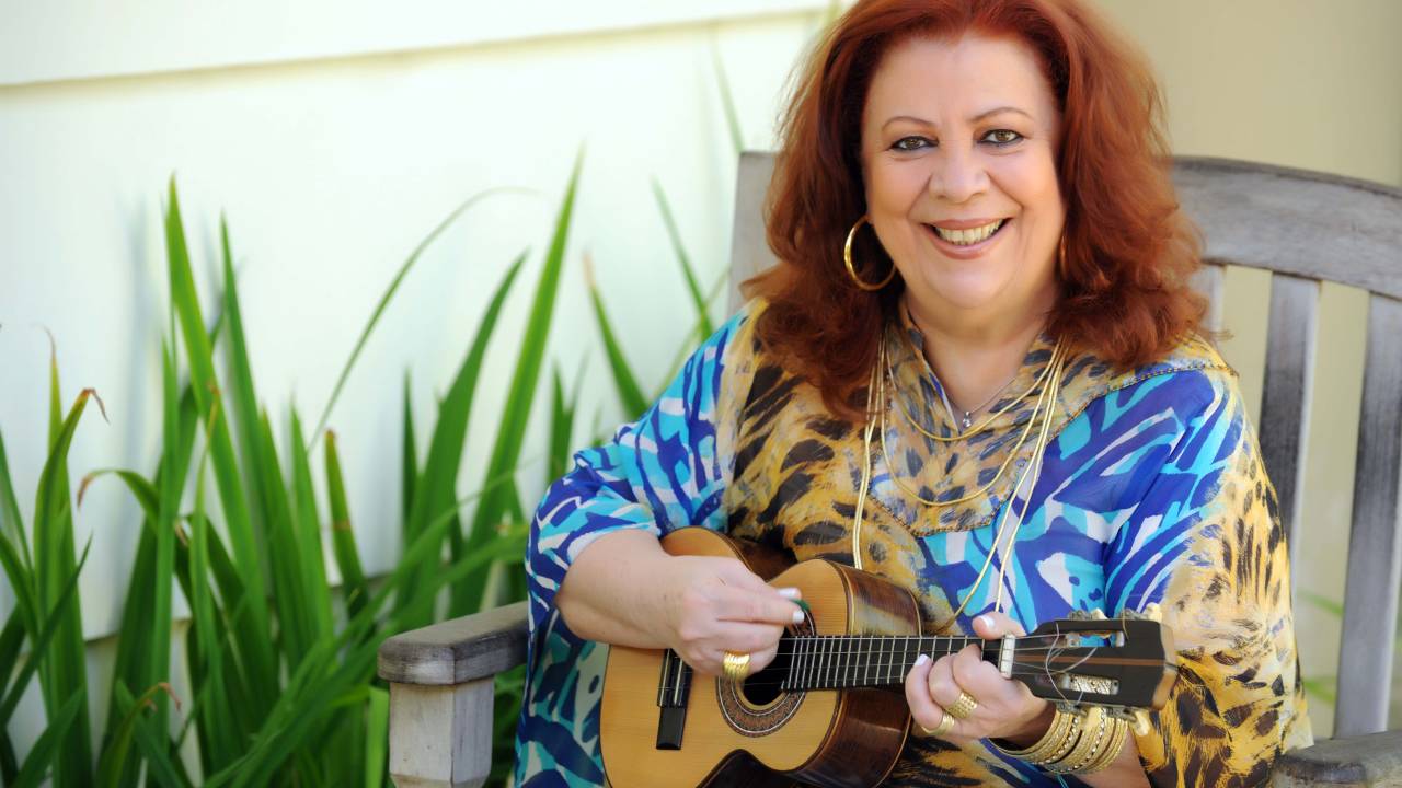 Cantora Beth Carvalho segurando um cavaquinho e sorrindo