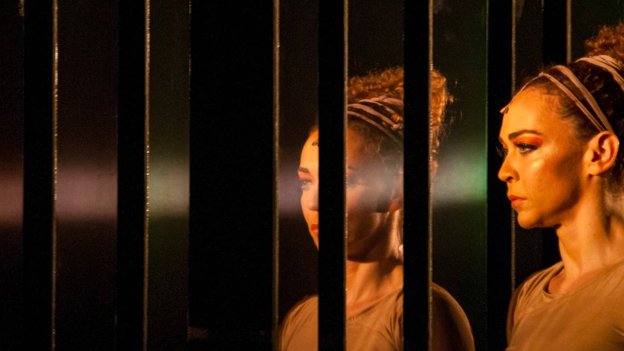 Atriz Laila Garin, no canto direito da foto, refletida em espelho, em cena, como Macabéa