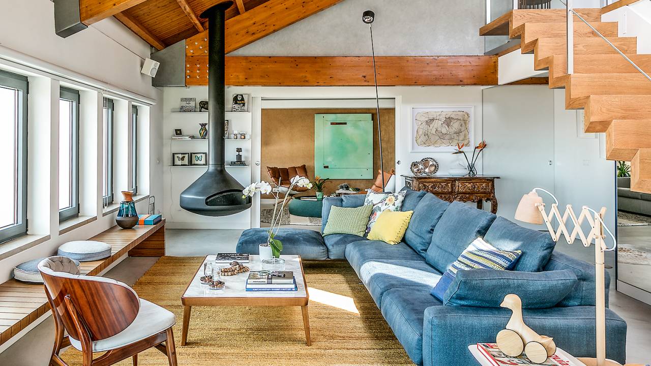 A imagem mostra um ambiente com sofás coloridos e piso e móveis em madeira