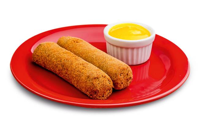 A imagem mostra dois croquetes de carne ao lado de mostarda sobre prato vermelho