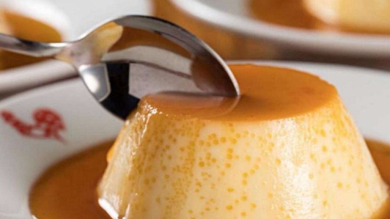 A imagem mostra uma colher prestes a partir um pudim de leite