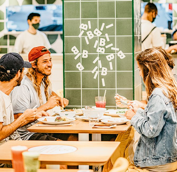 Lanchonete Bibi Sucos com clientes sorrindo e comendo nas mesas