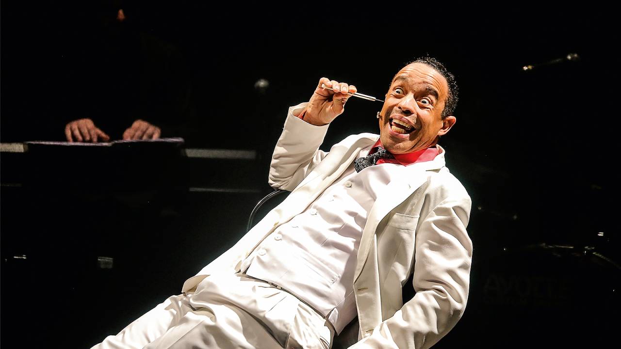 Édio Nunes em cena como Moreira da Silva, de terno
