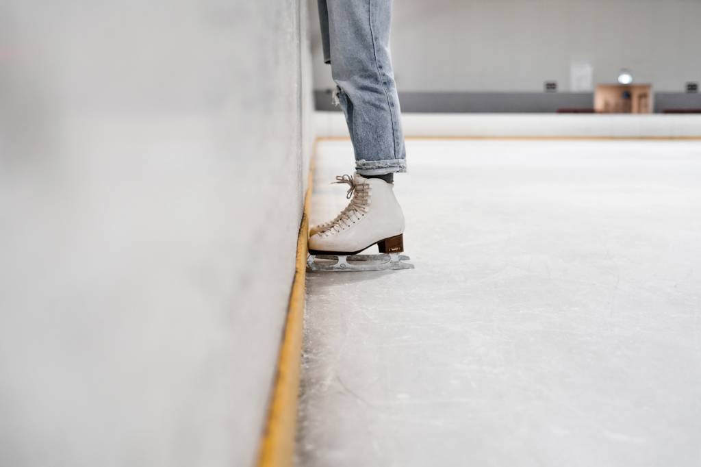 Pernas com patins numa pista de patinação no gelo