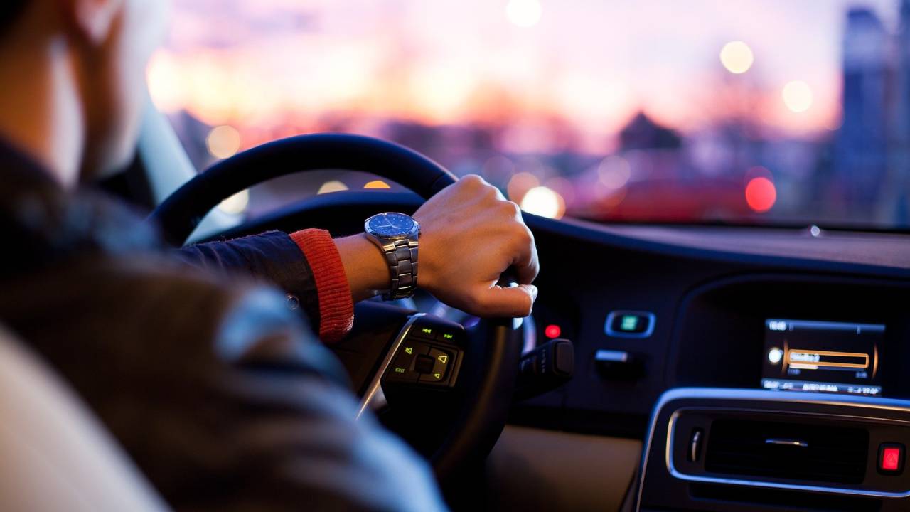 espaço interno de um automóvel com homem com mãos ao volante