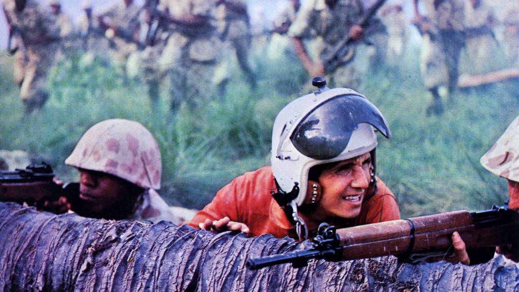 Filme Roberto Carlos Roberto Carlos jovem, de capacete, abaixado numa trincheira
