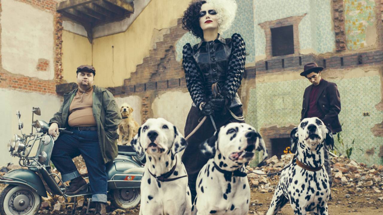 Emma Stone, como Cruella, segurando três dálmatas pela coleira