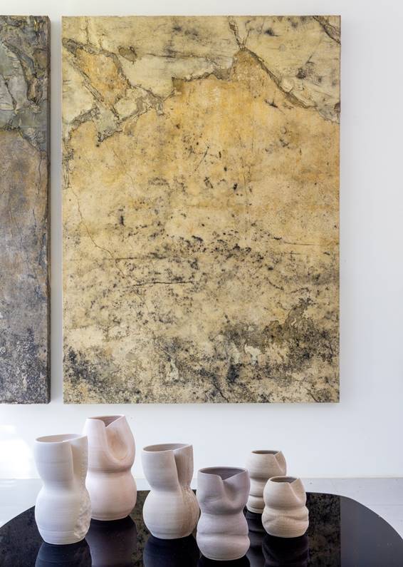 Quadro em tons de amarelo claro e cinza e pe&ccedil;as em cer&acirc;mica na frente