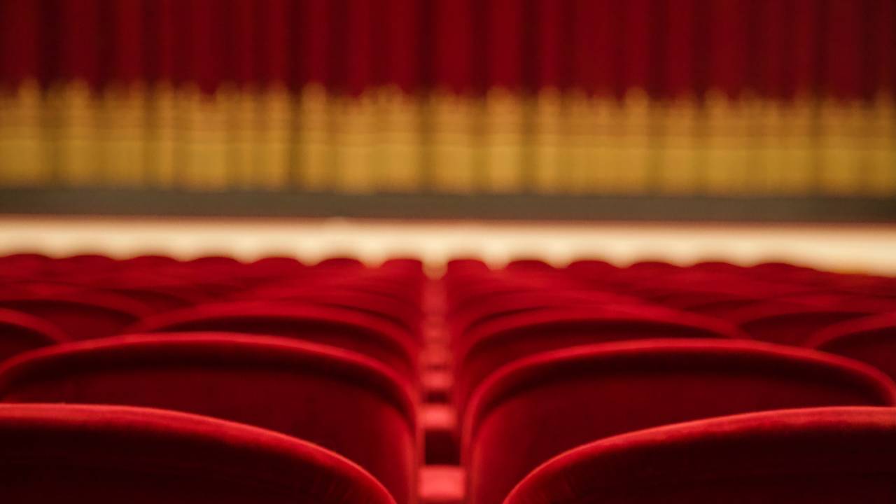 Teatro vazio, com palco com cortinas baixadas