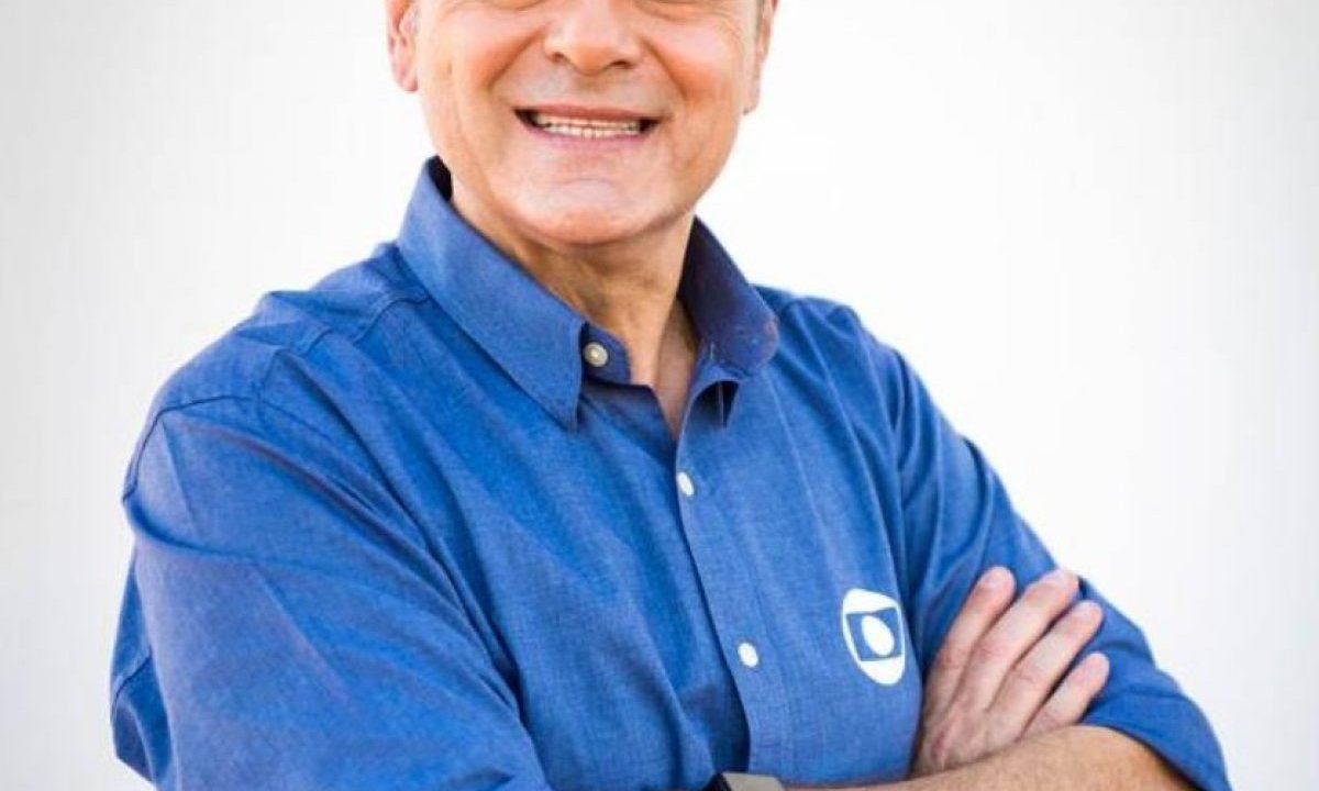 A imagem mostra o narrador Luis Roberto, de camisa azul com o logotipo da TV Globo