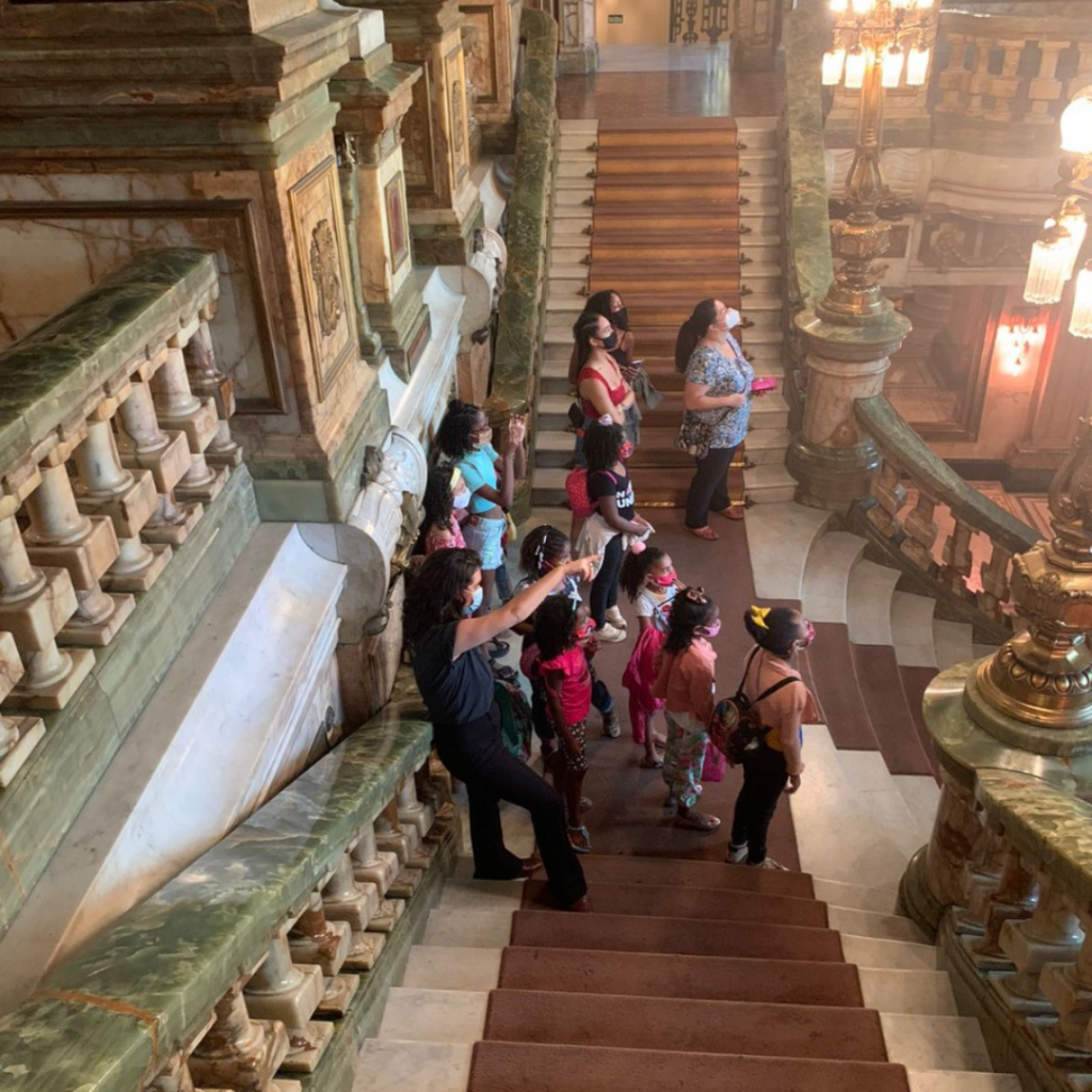 Foto mostra guia apresentando o Theatro Municipal do Rio para as crianças