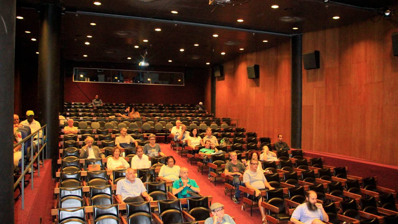 Foto da sala de cinema da Cinemateca do MAM com algumas pessoas nas poltronas