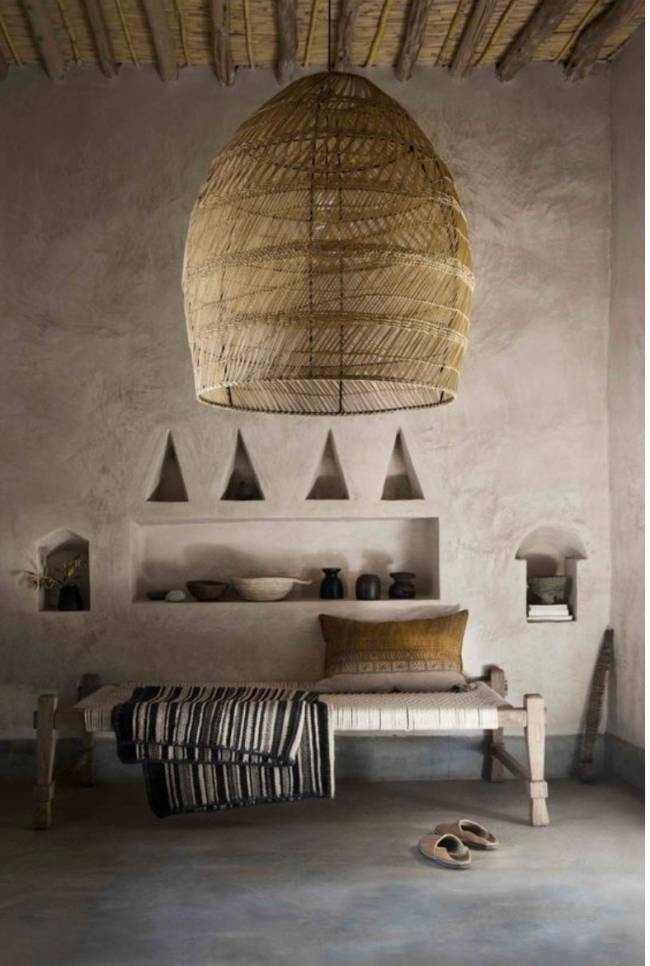 Wabi sabi A imagem mostra uma sala com lustre de palha, banco e almofada