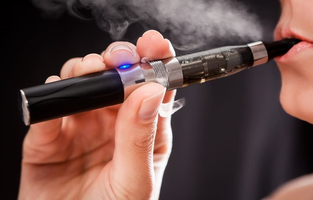 Mulher fuma cigarro eletrônico.