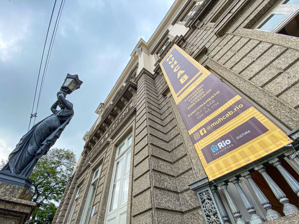 Foto da fachada do Muhcab com estátua no canto esquerdo da imagem e letreiro à direita