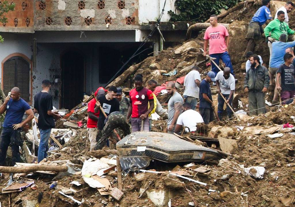 Bombeiros, moradores e voluntários trabalham no local do deslizamento no Morro da Oficina, após a chuva que castigou Petrópolis, na região serrana fluminense