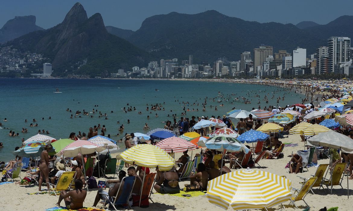 A Praia de Ipanema cheia em dia de sol, com o Morro Dois Irmãos