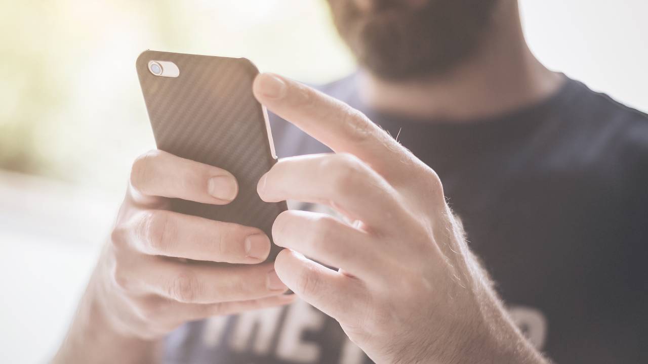 Homem segura um aparelho de celular.