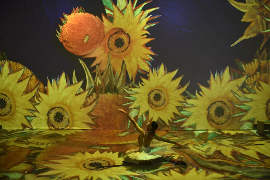 Projeção de girassóis, um dos temas mais marcantes dos quadros de Van Gogh, com uma bailarina interagindo com a projeção.