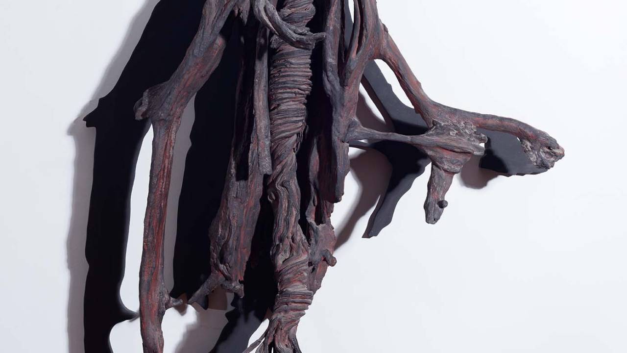 Escultura feita com pedaços de árvore pintados de preto.