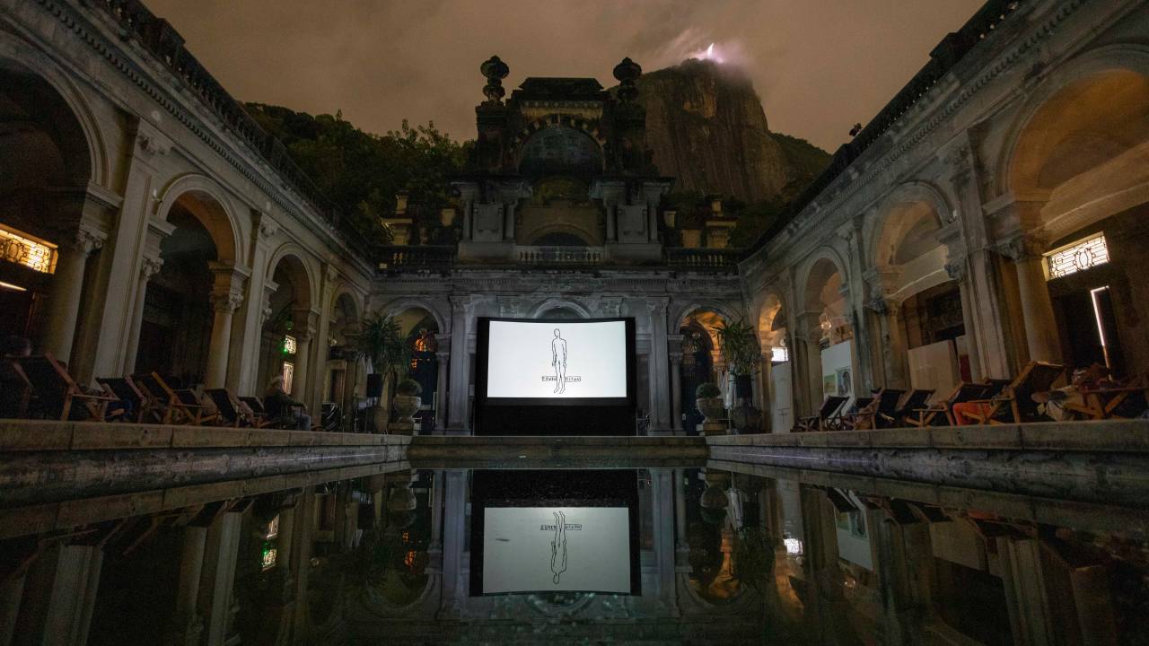 O interior da Escola de Artes Visuais Parque Lage, com a piscina, cadeiras em suas laterais e uma