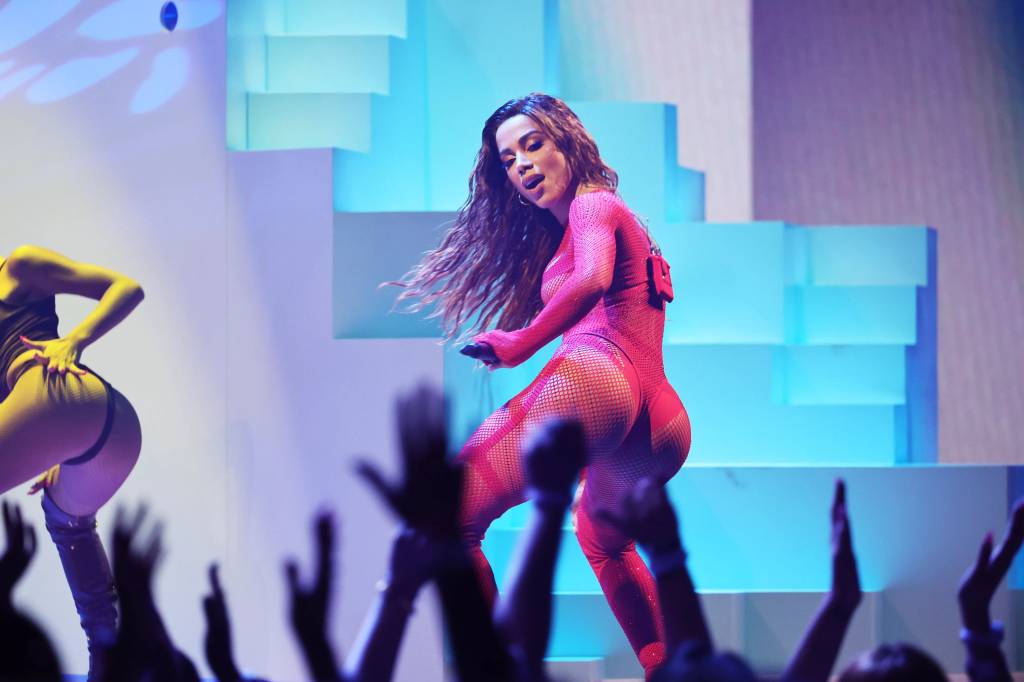 anitta getty images for mtv paramount g Foto de Anitta de lado, usando body vermelho, com o bumbum virado para o público. Em primeiro plano, desfocadas, as mãos do público para o alto.