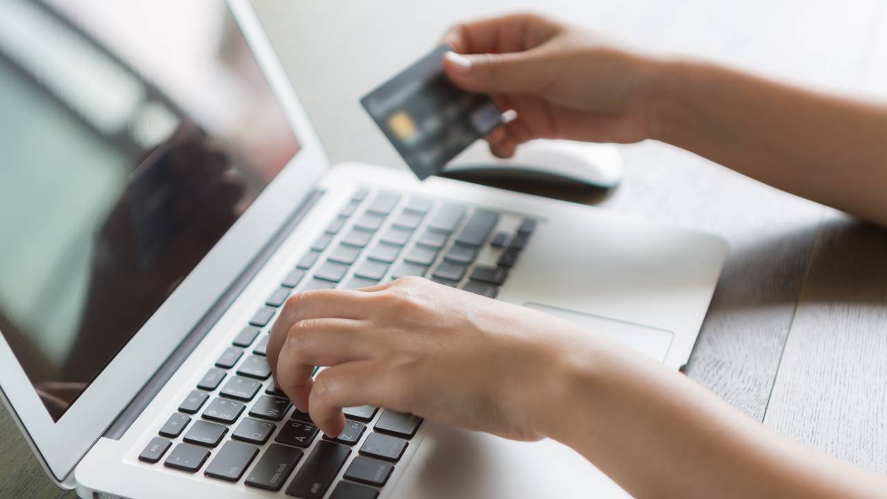 Foto mostra pessoa comprando com cartão de crédito pelo computador