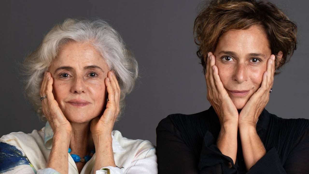 Foto mostra as atrizes Andréa Beltrão e Marieta Severo uma ao lado da outra com as mãos no rosto