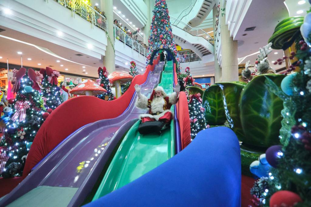 Natal West Shopping 2022 (2) Foto mostra Papai Noel escorregando em um tobogã que saide uma árvore de Natal