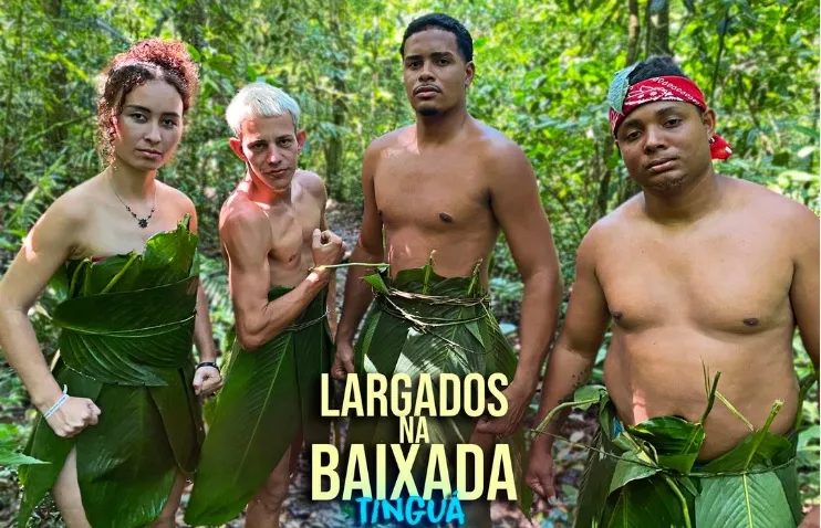 Uma mulher e quatro homens em um local cercado por natureza vestindo roupas de folha de bananeira