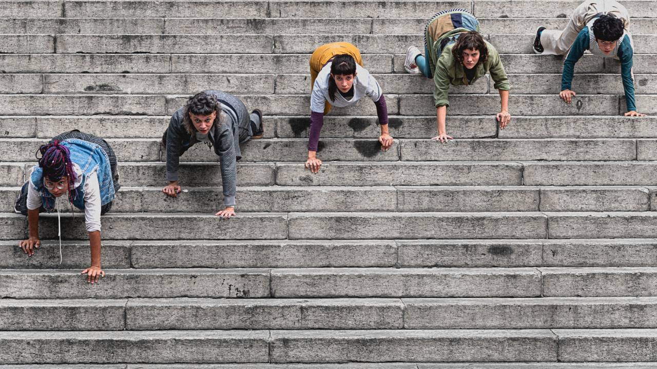 Cinco dançarinos do grupo Sats fazendo performance de dança em uma escada de concreto