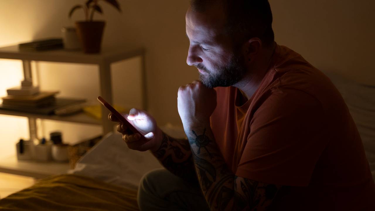 Homem é iluminado pela luz do celular.