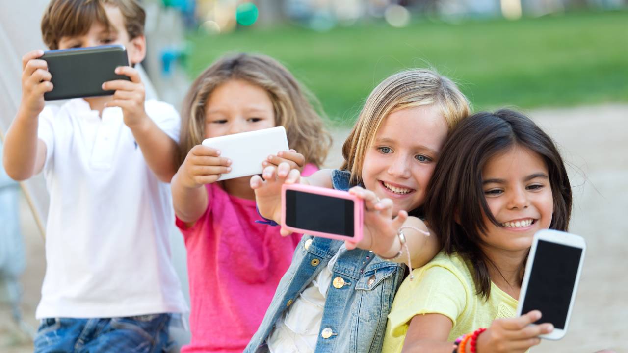 Quatro crianças seguram aparelhos celulares.
