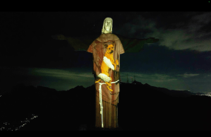 Estátua do Cristo com projeção estilo mapping que simula um abraço