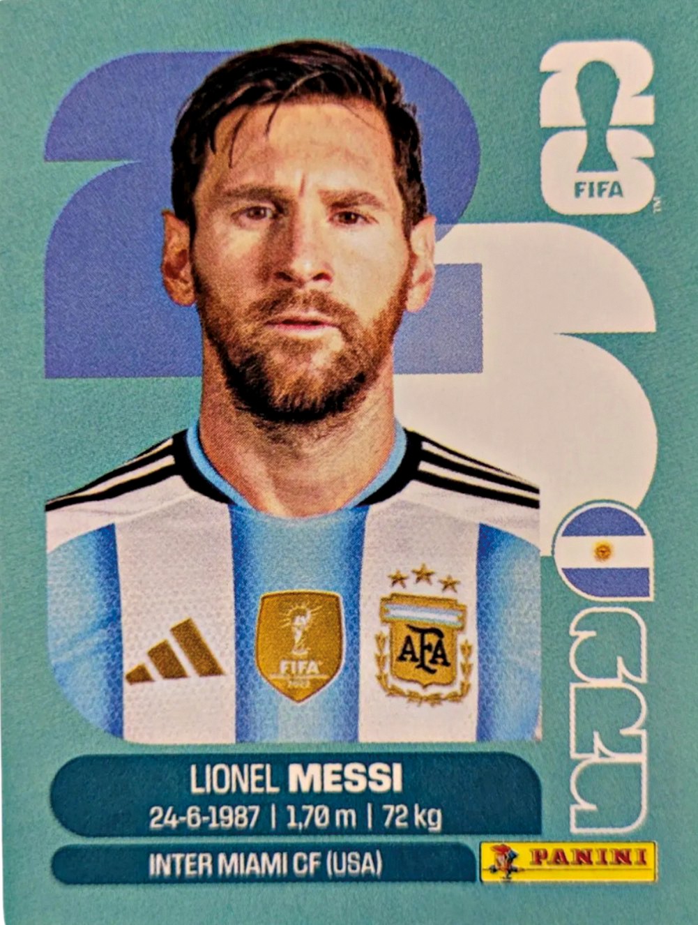 Cart&atilde;o de figurinha do jogador Lionel Messi, com barba, vestindo camisa azul e branca da Argentina, olhando para frente. Abaixo, seu nome, data de nascimento, altura, peso e clube Inter Miami CF (USA). No canto superior direito, o logo da FIFA. No canto inferior direito, o logo da Panini