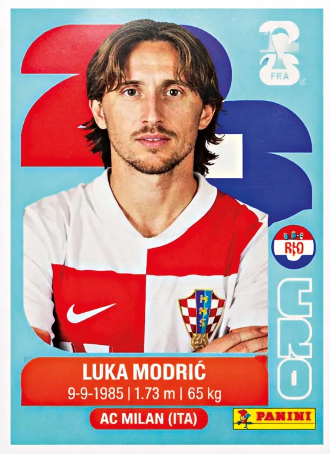 Cromo de Luka Modrić, jogador de futebol croata, com cabelo castanho e barba rala, vestindo camisa quadriculada vermelha e branca. Abaixo, seu nome, data de nascimento, altura, peso e clube AC Milan (ITA)