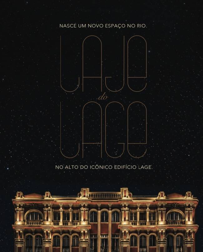 Fachada iluminada do Edif&iacute;cio Lage, com arquitetura cl&aacute;ssica em tons de vermelho e bege, sob um c&eacute;u noturno estrelado. Texto 
